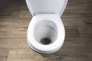 Tuvalet beyaz. Eski tarz tahtalardan yapılma zeminde duruyor. yakın plan.