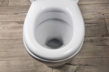 Tuvalet beyaz. Eski tarz tahtalardan yapılma zeminde duruyor. yakın plan.