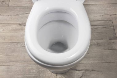 Tuvalet beyaz. Eski tarz tahtalardan yapılma zeminde duruyor. yakın plan.