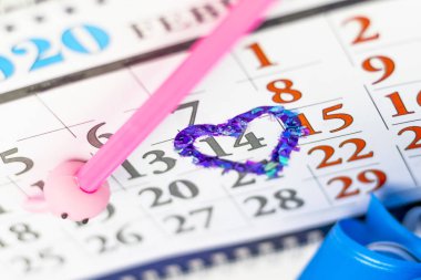 Masa takvimi, pembe kalem. Kırmızıyla çevrelenmiş, kalp şeklinde. Bir hediye kutusu var..