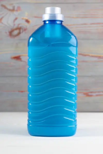 En plastflaska fylld med blå vätska. På en trä bakgrund retro stil. Närbild — Stockfoto