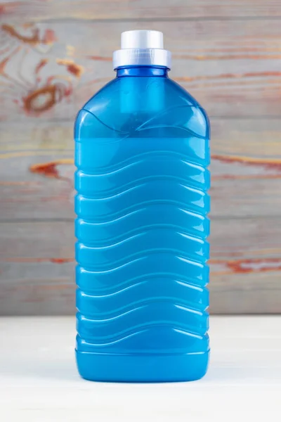 A plastic bottle filled with blue liquid. On a wooden background retro style. Close-up — Stock Photo, Image