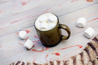 Şekerleme. Retro tarzı ahşap arka plan. İçinde marşmelov olan cam bardak. Yünlü bir eşarp da var. Yakın plan. Renkli