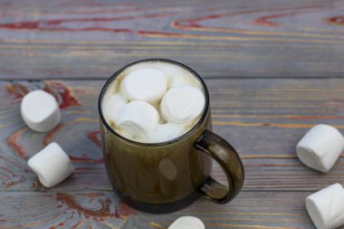 Şekerleme. Retro tarzı ahşap arka plan. İçinde marşmelov olan cam bardak. Yünlü bir eşarp da var. Yakın plan. Renkli