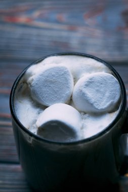 Şekerleme. Retro tarzı ahşap arka plan. İçinde marşmelov olan cam bardak. Yünlü bir eşarp da var. Yakın plan. Renkli