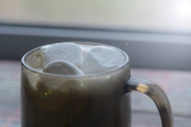 Şekerleme. Retro tarzı ahşap arka plan. İçinde marşmelov olan cam bardak. Yünlü bir eşarp da var. Yakın plan. Renkli