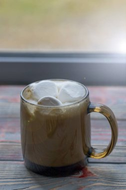 Şekerleme. Retro tarzı ahşap arka plan. İçinde marşmelov olan cam bardak. Yünlü bir eşarp da var. Yakın plan. Renkli