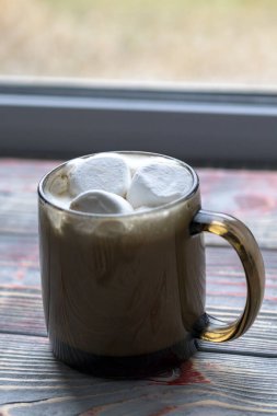 Şekerleme. Retro tarzı ahşap arka plan. İçinde marşmelov olan cam bardak. Yünlü bir eşarp da var. Yakın plan. Renkli