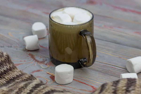 Marshmallow. Sfondo in legno stile retrò. Tazza di vetro con marshmallow dentro. C'è anche una sciarpa di lana. Primo piano. Colorato — Foto Stock