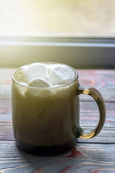 Malvavisco. Fondo de madera estilo retro. Taza de cristal con malvavisco. También hay una bufanda de lana. Primer plano. Teñido — Foto de stock gratis