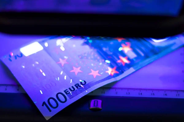 100 eurobankbiljet. Liggend in het ultraviolet om de echtheid van bankbiljetten te verifiëren. Close-up — Stockfoto
