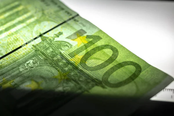100 Euro banknote. Lying in the ultraviolet to verify the authenticity of banknotes. Close-up — Stock Photo, Image