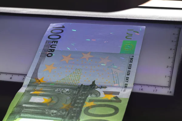100 євро на банкноті. Лежачи в ультрафіолеті, щоб перевірити автентичність банкнот. Підсумок. — стокове фото