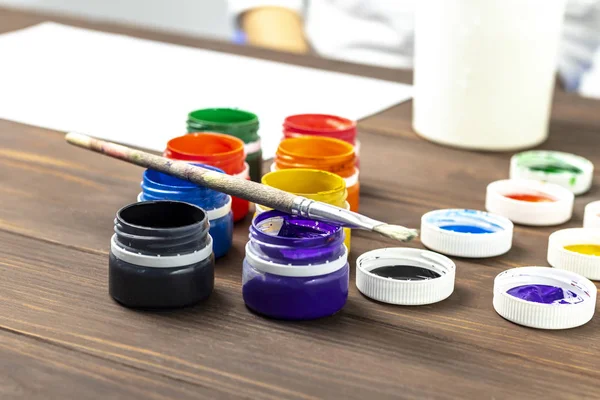 Eski tarz ahşap arka plan. Kutularda boya ve boya fırçası var. Yakın plan. Renkli