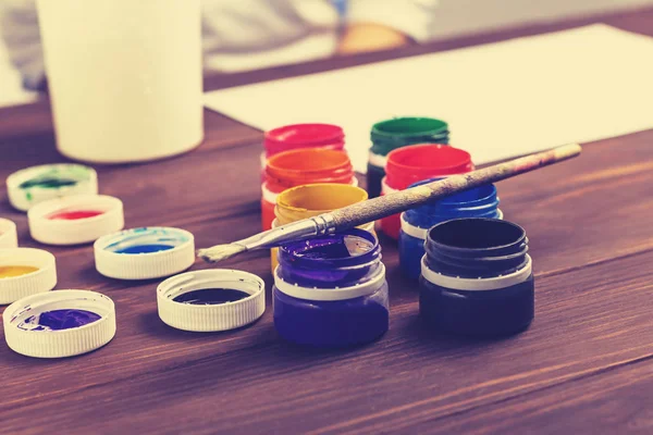Eski tarz ahşap arka plan. Kutularda boya ve boya fırçası var. Yakın plan. Renkli