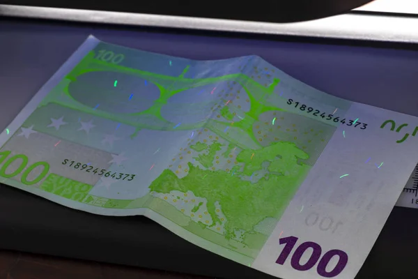 100 Euro banknote. Lying in the ultraviolet to verify the authenticity of banknotes. Close-up — Stock Photo, Image