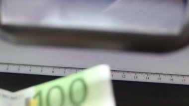 Erkek el, 100 avroluk ultraviyole ışığın orijinalliğini doğrulayacak. Yakın plan.