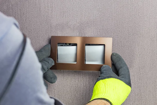 De hoofdelektricien stelt de schakelaar in. Een close-up. De kamer is gekleurd. De schakelaar is bruin. De sleutels zijn van zilver. Er is een tint. — Stockfoto