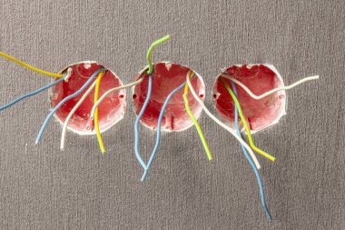 3 kutu kırmızı renk. Duvar monte edildi. Onlardan biri farklı renklerde kablolar çıkarır. Yeşil, beyaz, mavi. Yakın plan..