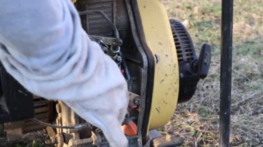 Yakın plan. Usta, istasyonu elle çalıştırarak elektrik üretmeye başlar..