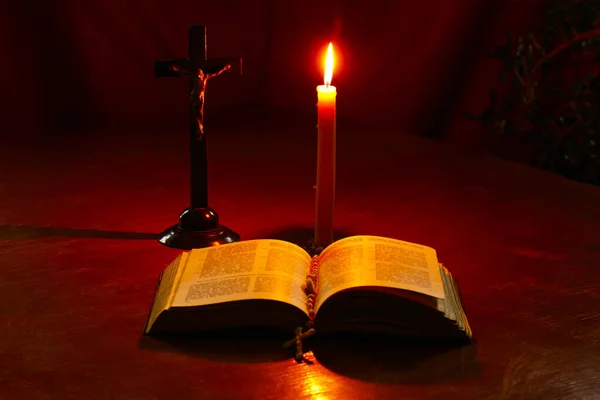 Mesa de vidrio manchado de madera. Hay un libro en él. en ella hay una cruz, una vela está ardiendo. Luz tenue. Oscuridad. Hay un tinte —  Fotos de Stock
