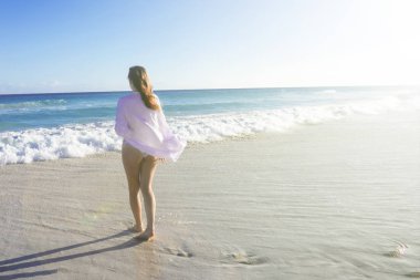 Okyanus. Yaz. Kot pantolonlu bir kız sırtı bize dönük olarak sahile gidiyor. Boşluğu kopyala