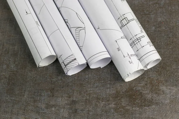 Wooden background. On it are blueprints or a plan of the future home or knowledge. They are rolled up.