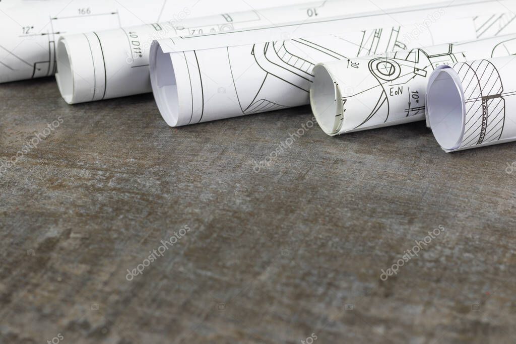 Wooden background. On it are blueprints or a plan of the future home or knowledge. They are rolled up.