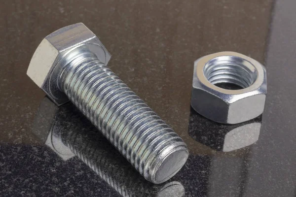 Cover the bolt and nut with galvanization. A polished stone of dark color lies on a piece. Close-up