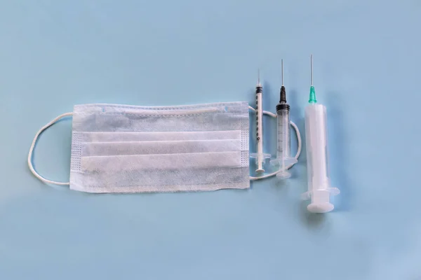 Máscara médica para proteção contra bactérias em um fundo azul. Perto de seringas para injectáveis. Close-up — Fotografia de Stock
