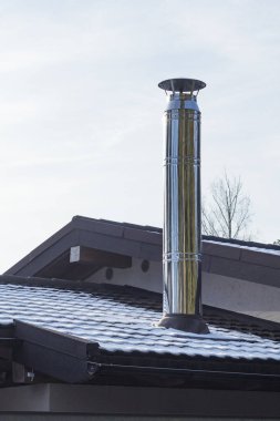 Açık havada. Karanlık bir çatıda paslanmaz çelik baca. Çok fazla kar yok. Yakın plan..