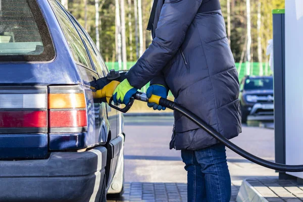 暖かいジャケットの女の子は黄色い手袋で車を給油します — ストック写真