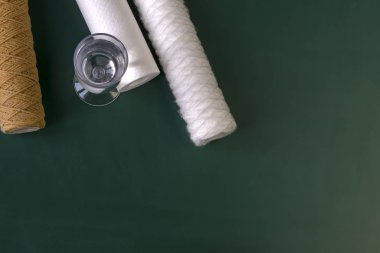 Su filtresi iki ünite ve değiştirilmesi gereken bir kartuş. Bir bardak temiz suyun yanında. Geçmişe dönük ahşap bir arka plan. Yakın plan..