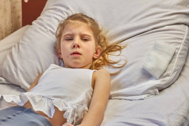 Sarışın kız yatakta yatıyor. Yakın plan. Rengi var..