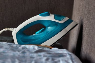 Koyu renk. Ütü bir ütü masasının üzerinde, koyu bir zemin üzerinde. Yakın plan..