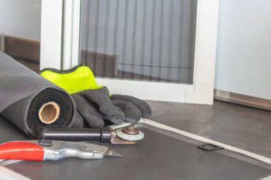 Yapım odası. Ön planda bir rulo sivrisinek ağı. Arka planda sineklere karşı birkaç çerçeve var. Sert gölgeler