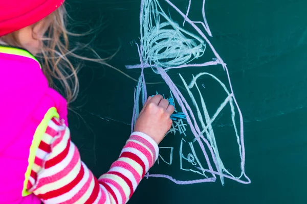 Девушка Розовой Куртке Рисует Мелом Школьной Доске Дом Руках Мелок — стоковое фото