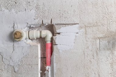 Boru gri PVC 'den yapıldığı için duvar bir hendeğe yapıştırılmış. Isıtıcıyı bağlayacak çıkış. Yakın plan.