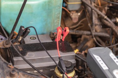 İçten yanmalı motorlu bir araba. Motor kapağı açık ve aküsü de tamir ediliyor..