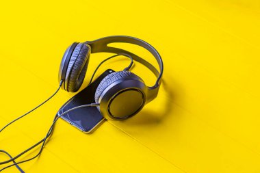 Tahta arka plan sarı retro tarzında. Üzerinde siyah kulaklıklar ve telin bir kısmı var..