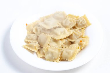 Beyaz arka planda. Beyaz bir tabak yuvarlak, üzerinde birkaç mantı var ve buhar geliyor. Bir gölge var. Yakın plan..