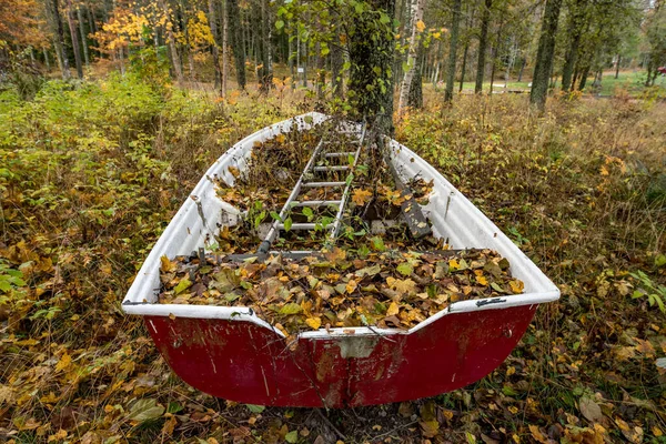 Viejo barco en octubre con un montón de hojas — Foto de Stock