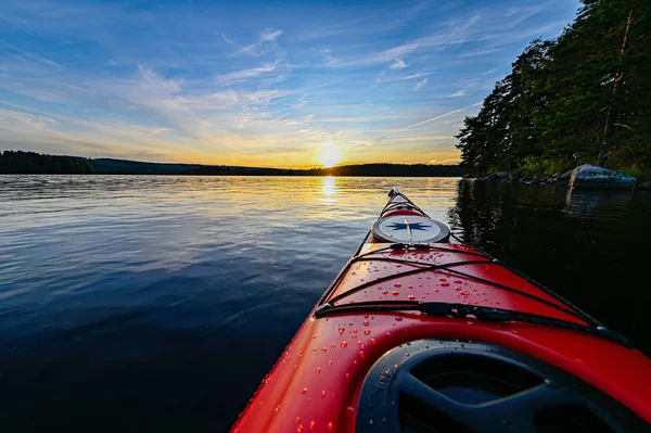 Červená plastová kajak na klidné vodě při západu slunce — Stock fotografie