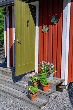 kırmızı ahşap bir kulübenin önündeki merdivenlerde çiçekler.