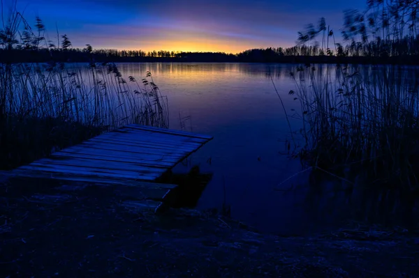 Sunrise over wooden jetty and frozen lake — Stock Photo, Image