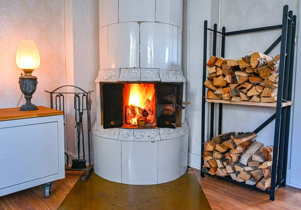 Fuego en una estufa de azulejos en una cabina — Foto de Stock