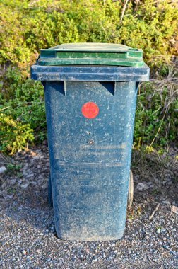 gabage can standing near a gravel road