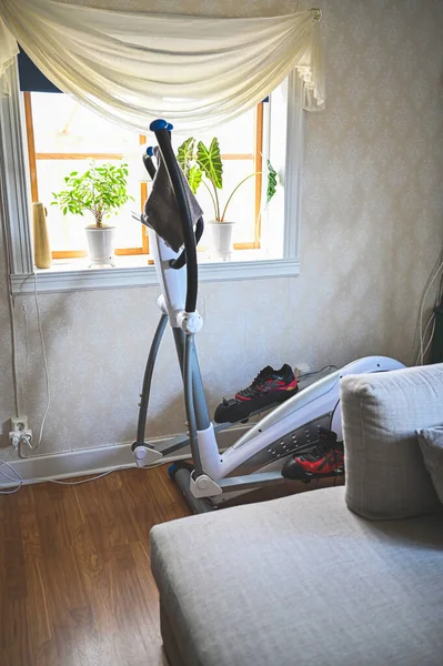 fitness equipment crosstrainer behind sofa in livingroom