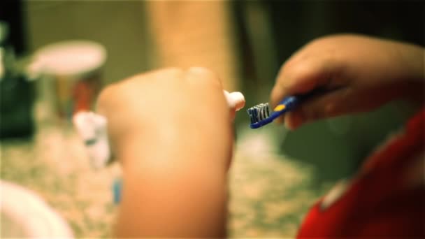 小さな男の子の手バスルームで歯ブラシに歯磨き粉を入れて — ストック動画