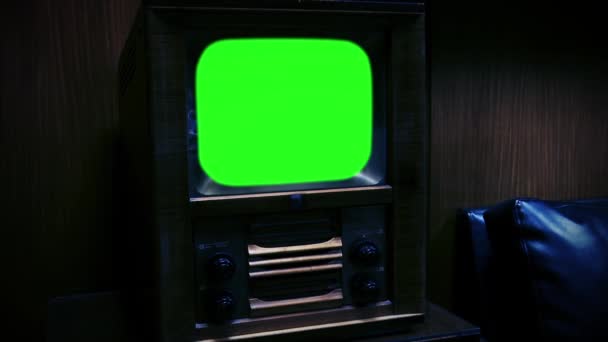 夜に黒のソファの近くの部屋で緑の画面でレトロ50テレビ ズームアウトショット 緑の画面を必要な映像や画像に置き換えることができます Effects でキーエフェクトで操作できます Youtubeでチュートリアルをチェック — ストック動画